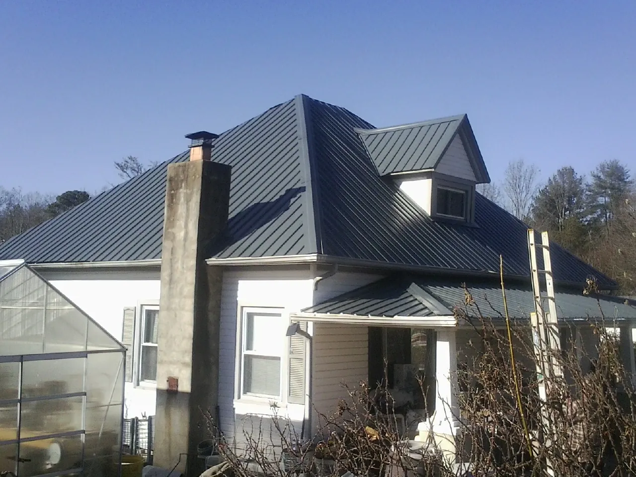 Dark blue standing seam metal roof on a white farmhouse with dormer — Slate & Tile Roof Repair by Roofing Brothers in Basin