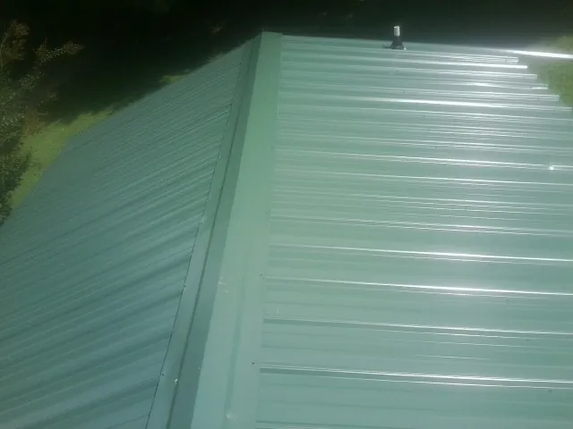 New green metal panels meeting at the ridge of a roof — Flat Roof Repair work by our crew in Basin