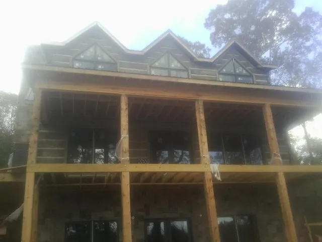 Dormers and porch framing on a large log home under construction — Roof Coating work by our crew in Basin