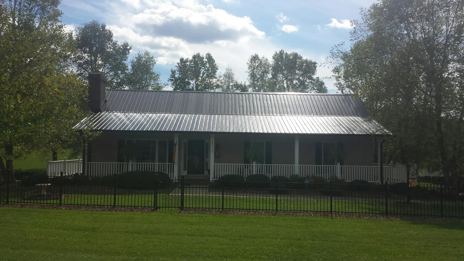 Gray metal roof on a brick ranch with a full width front porch — Gutter Guard Installation work by our crew in Basin